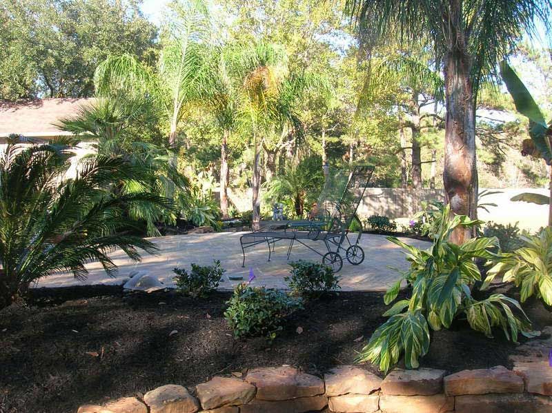 Outdoor limestone patio surrounded by a landscaped garden of plants