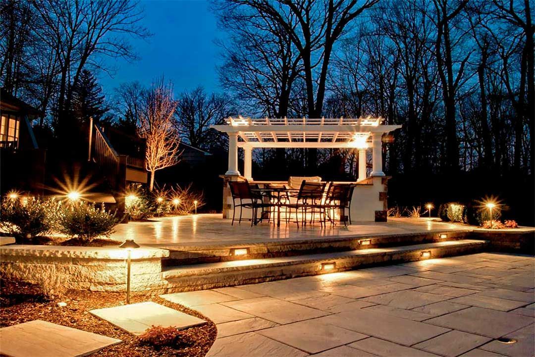 Outdoor lighting for a paver patio with staircase and a pergola