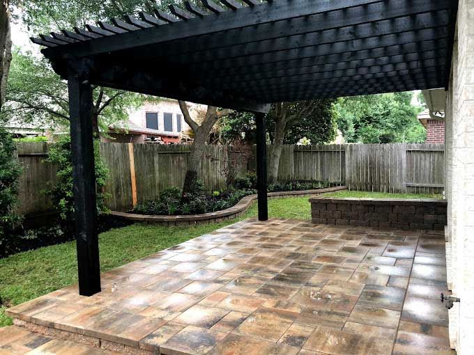 Backyard limestone patio covered with a pergola