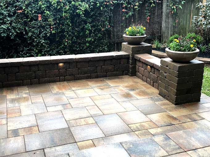 Patio with large shiny limestone and a small wall of square stones.