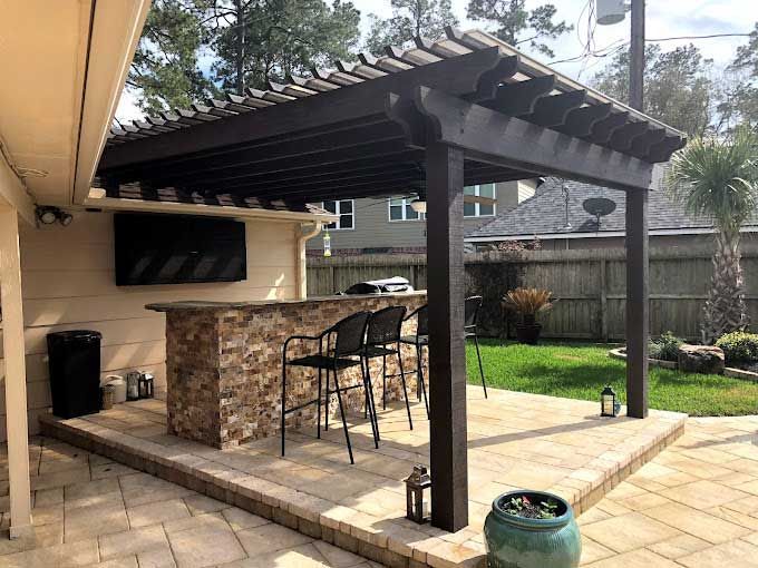 Custom outdoor kitchen covered by a dark cedar pergola