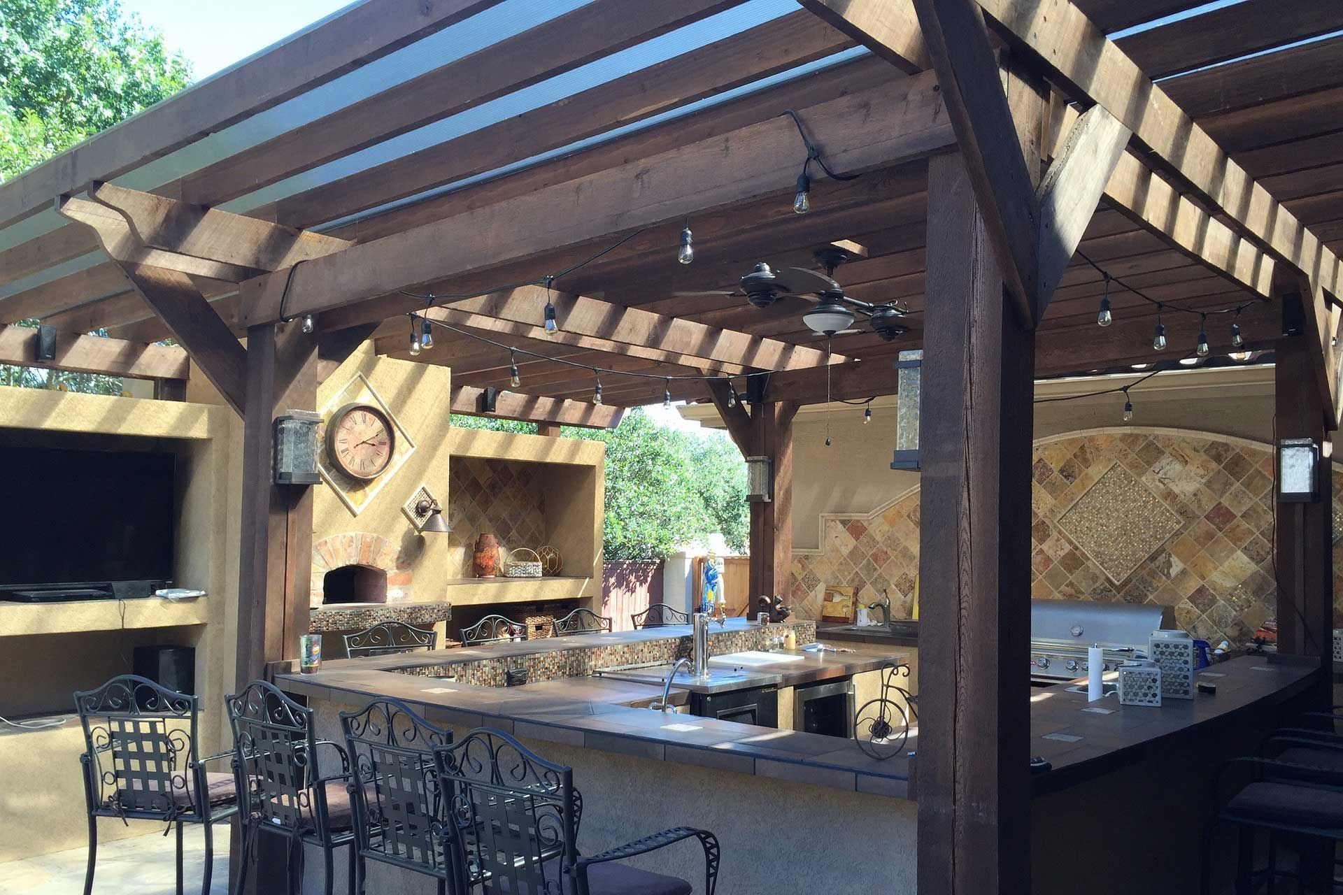 Custom cedar pergola with clear roof, outdoor kitchen and bar