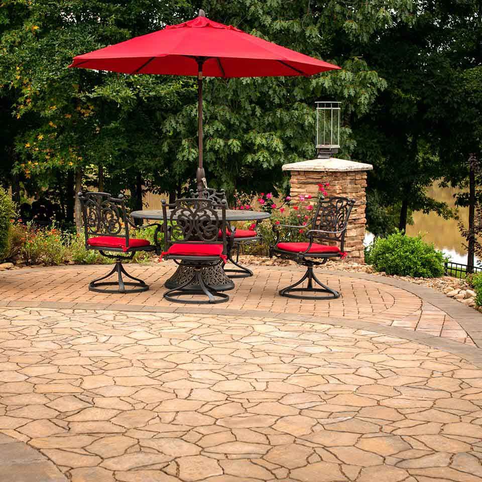 A patio with a red umbrella and table with chairs set up on its side