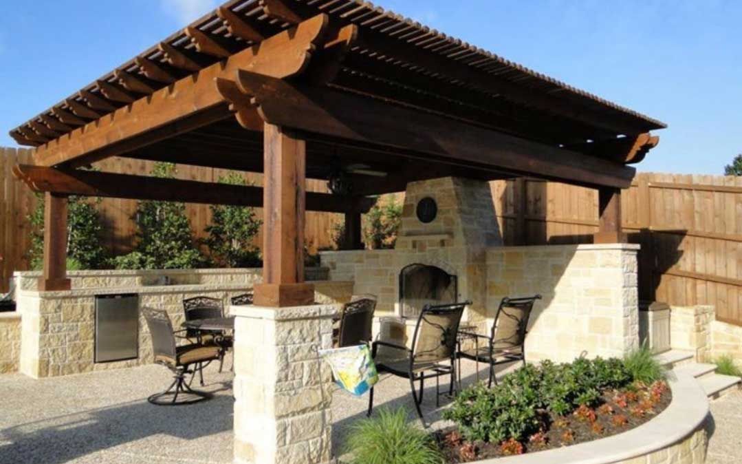 Patio of clear stones covered by a cedar pergola with a fireplace