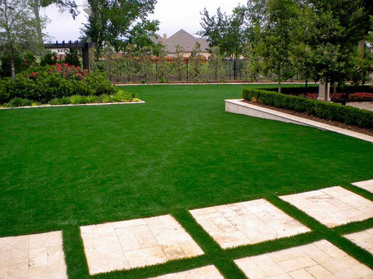 Artificial turf green with landscaping and stone pathways