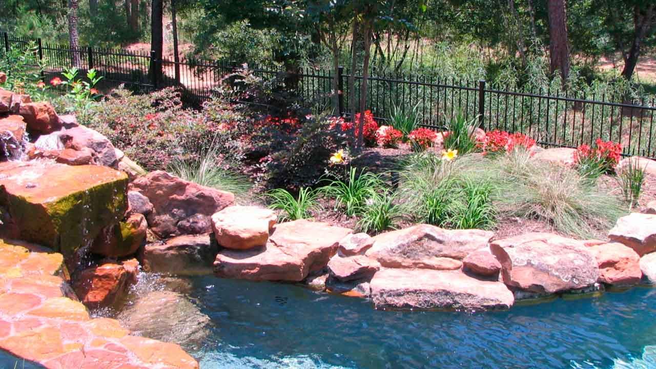 A small pond with flower and plants landscaping and a water cascade