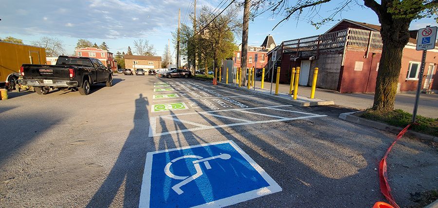 Parking lot with disabled parking spaces marked with blue and white symbols. A black pickup truck is parked in the lot.