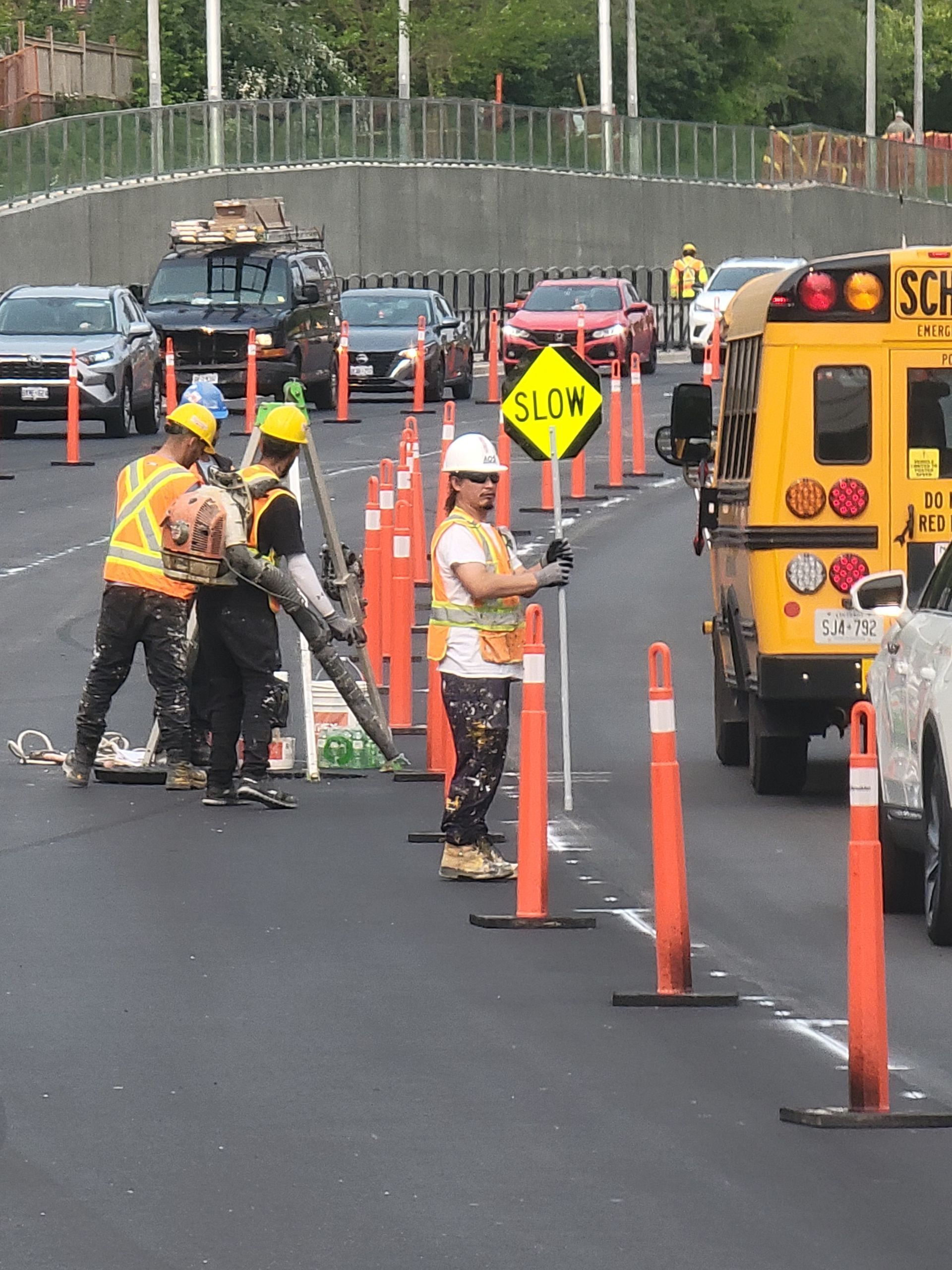 Road construction with workers, cones, slow sign, and vehicles.