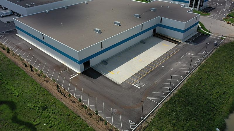 Aerial view of a large industrial building with a loading dock and parking lot.