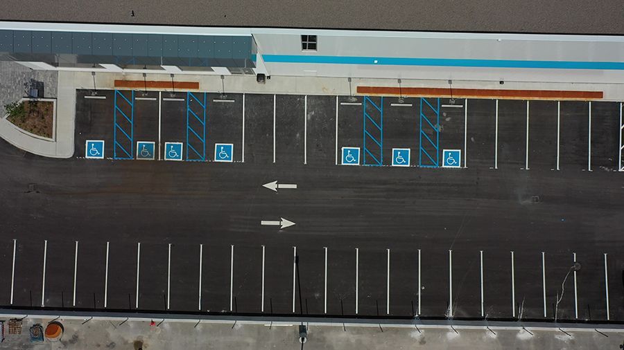 Aerial view of a mostly empty parking lot with several designated handicap parking spaces in front of a building.