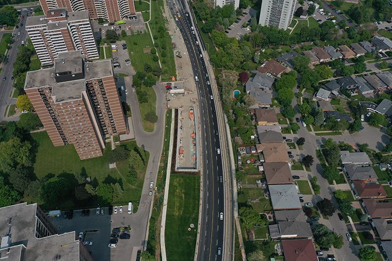 Aerial view of a highway with construction in the median; apartment buildings and houses on either side.