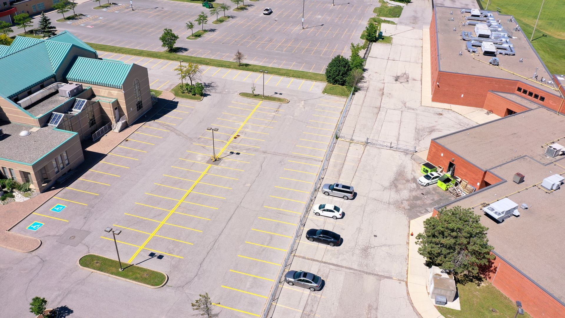 Aerial view of a mostly empty parking lot with a few parked cars and surrounding brick buildings.