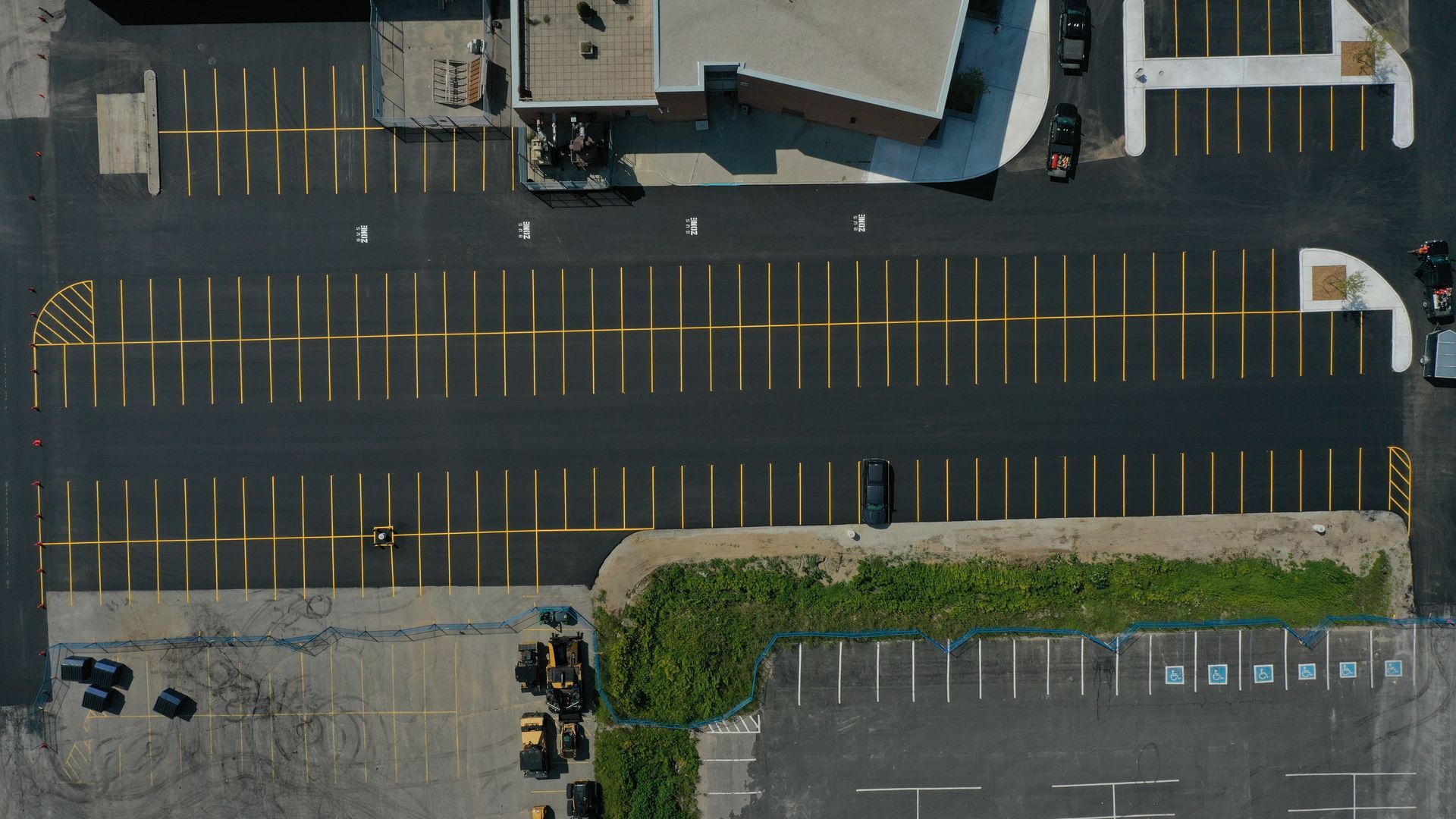 Overhead view of a paved parking lot with yellow painted lines.
