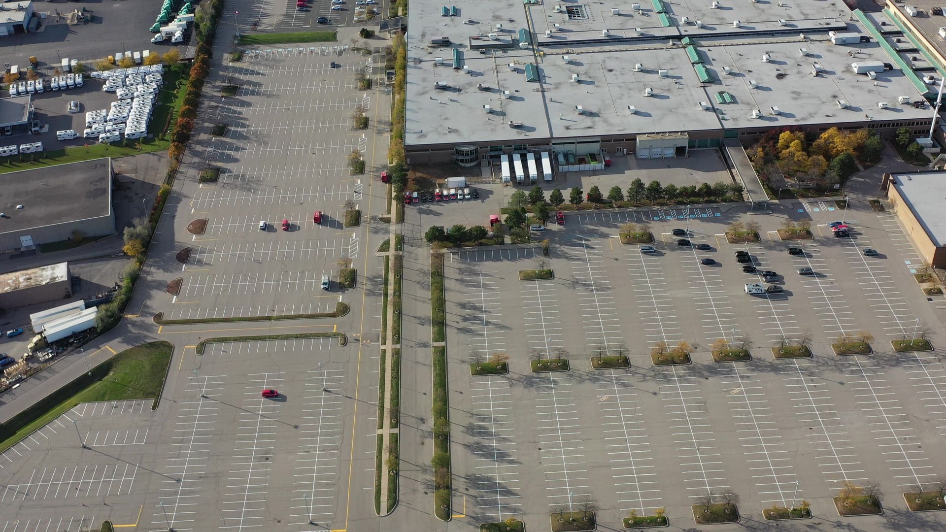Aerial view of a mostly empty parking lot in front of a large commercial building; several cars are present.