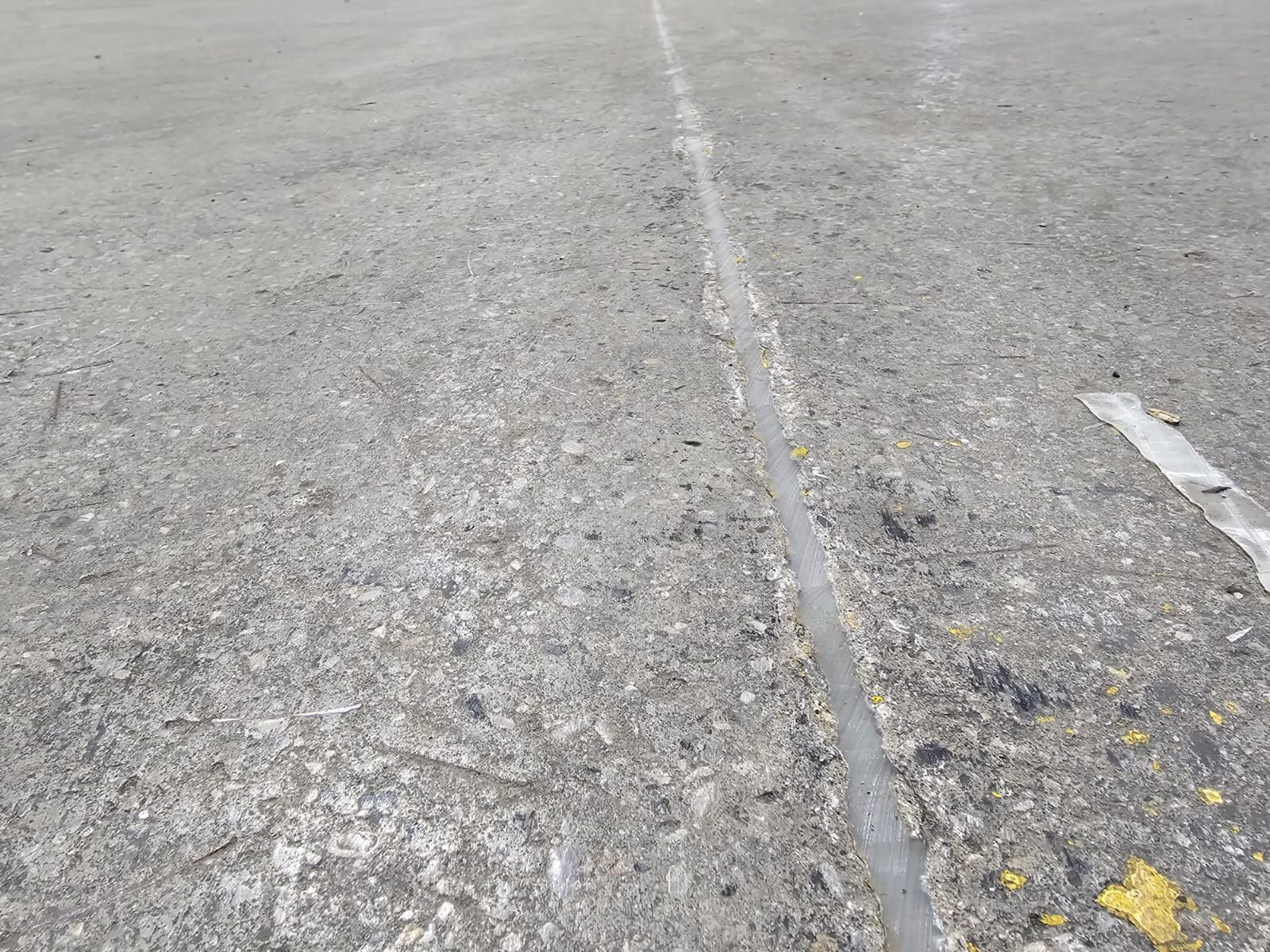 Concrete surface with a white line down the center, possibly a road or walkway.