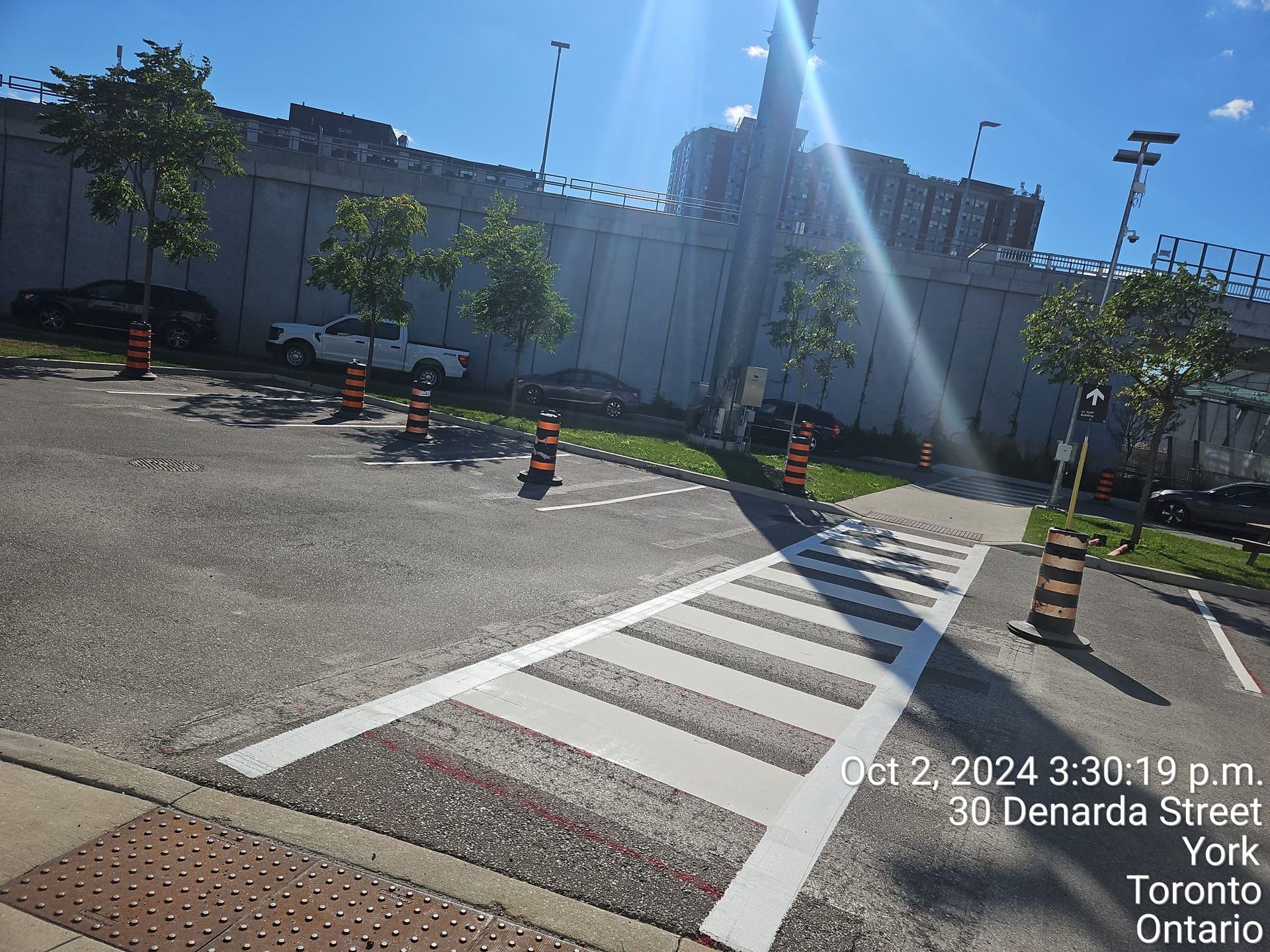 Crosswalk on asphalt with cones, near a wall and trees, 30 Denarda Street, York, Ontario.