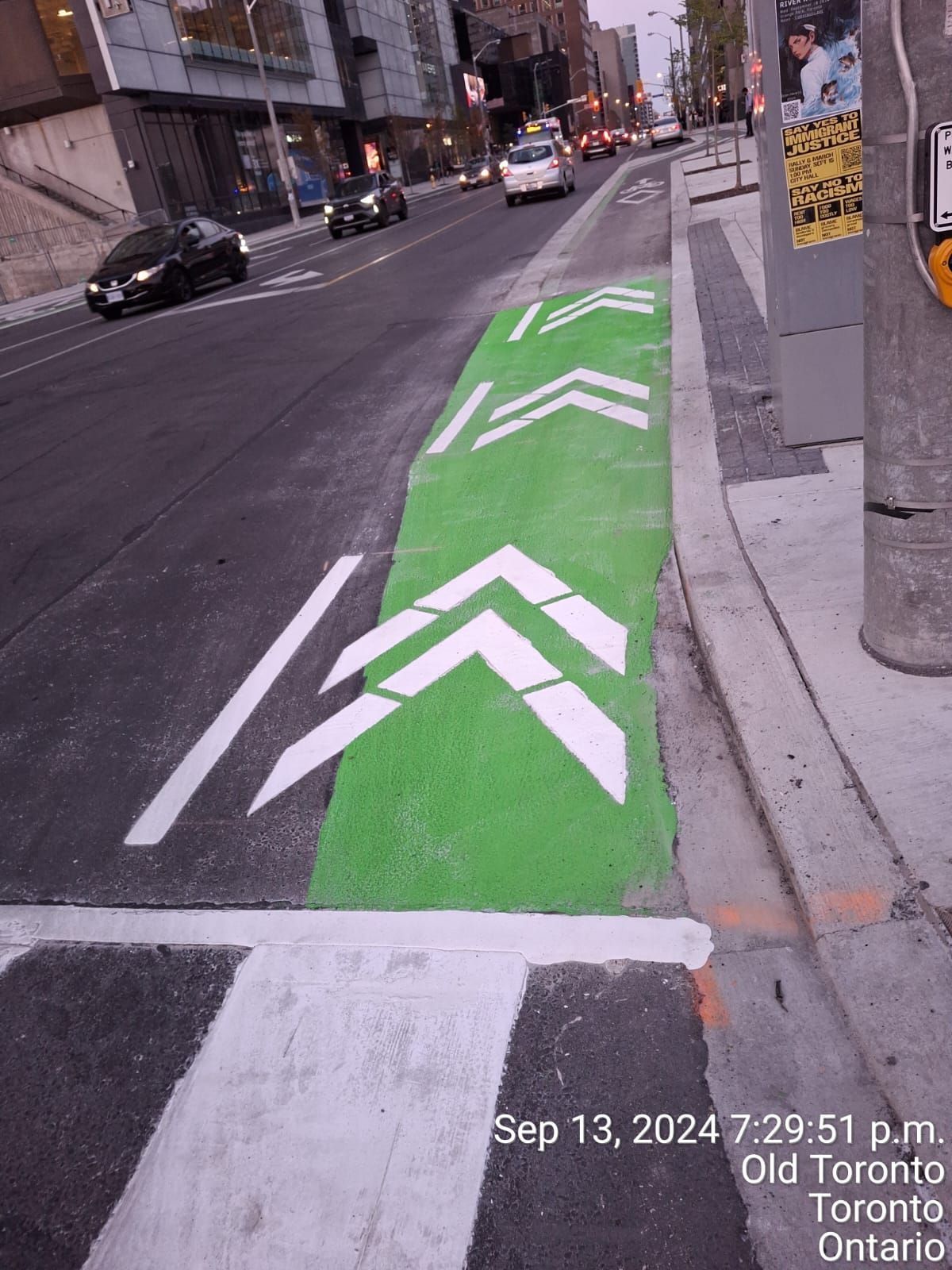 Green painted bike lane with white directional arrows, on a city street.