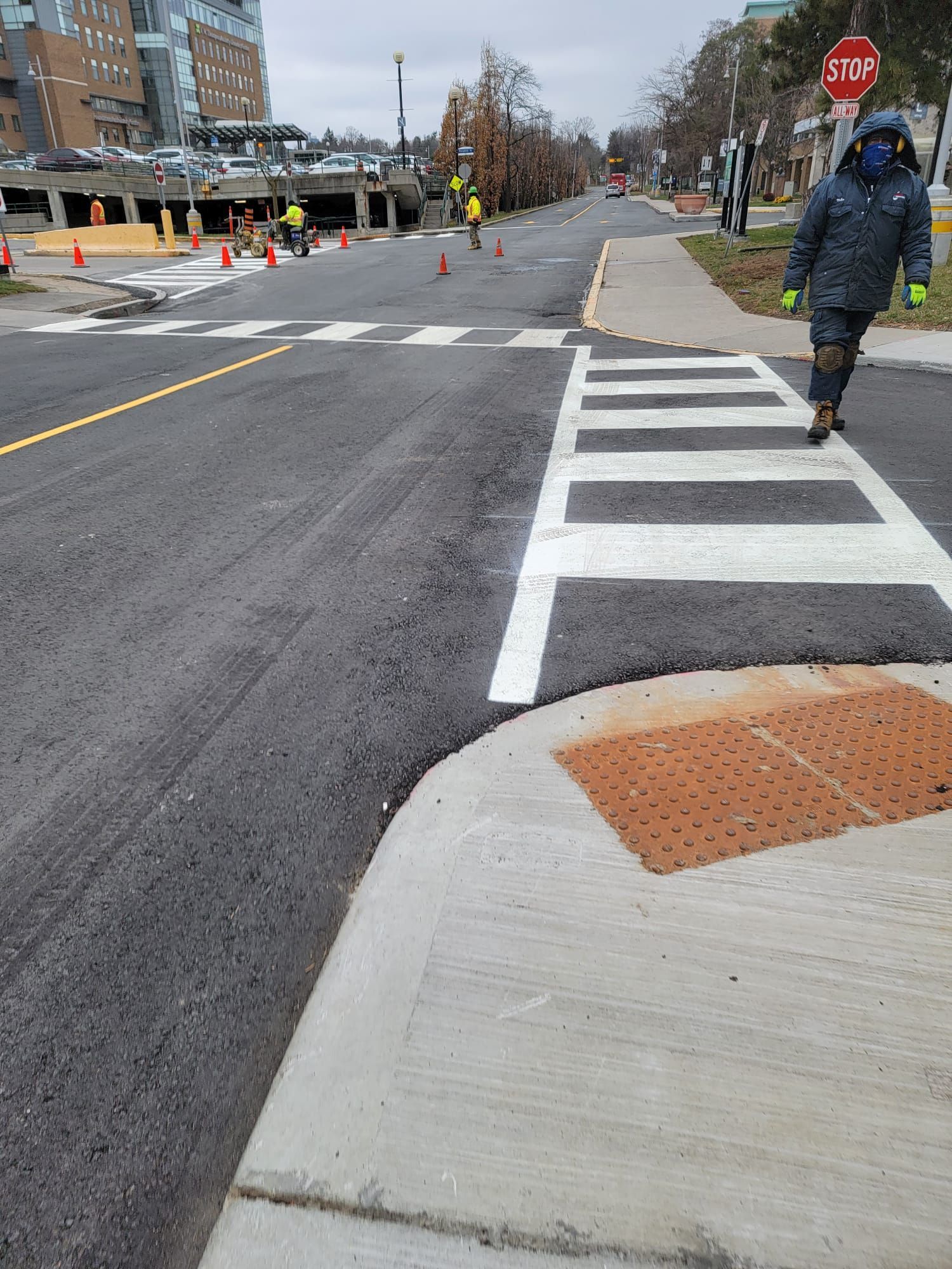 Person crossing newly paved crosswalk with construction in the background.