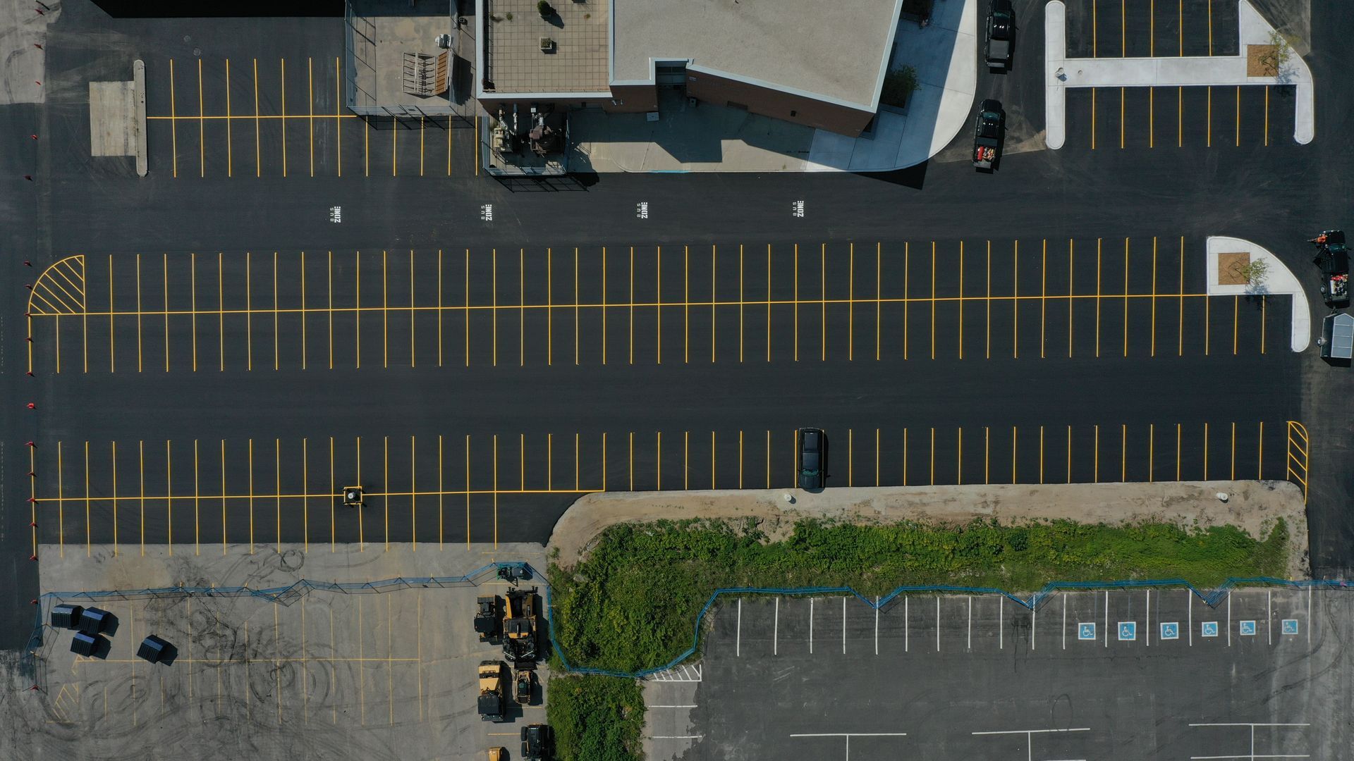 Overhead view of a freshly paved parking lot with yellow painted parking space lines.