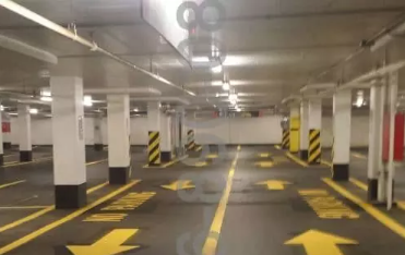 An empty parking garage with painted arrows and support pillars.
