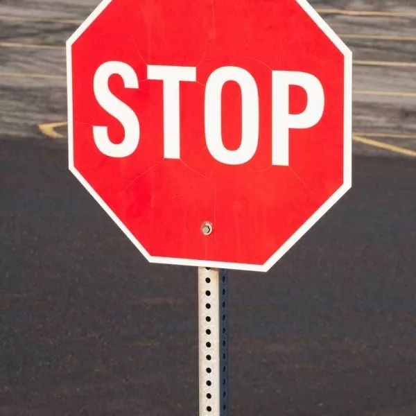 Red stop sign with white text on a metal post.