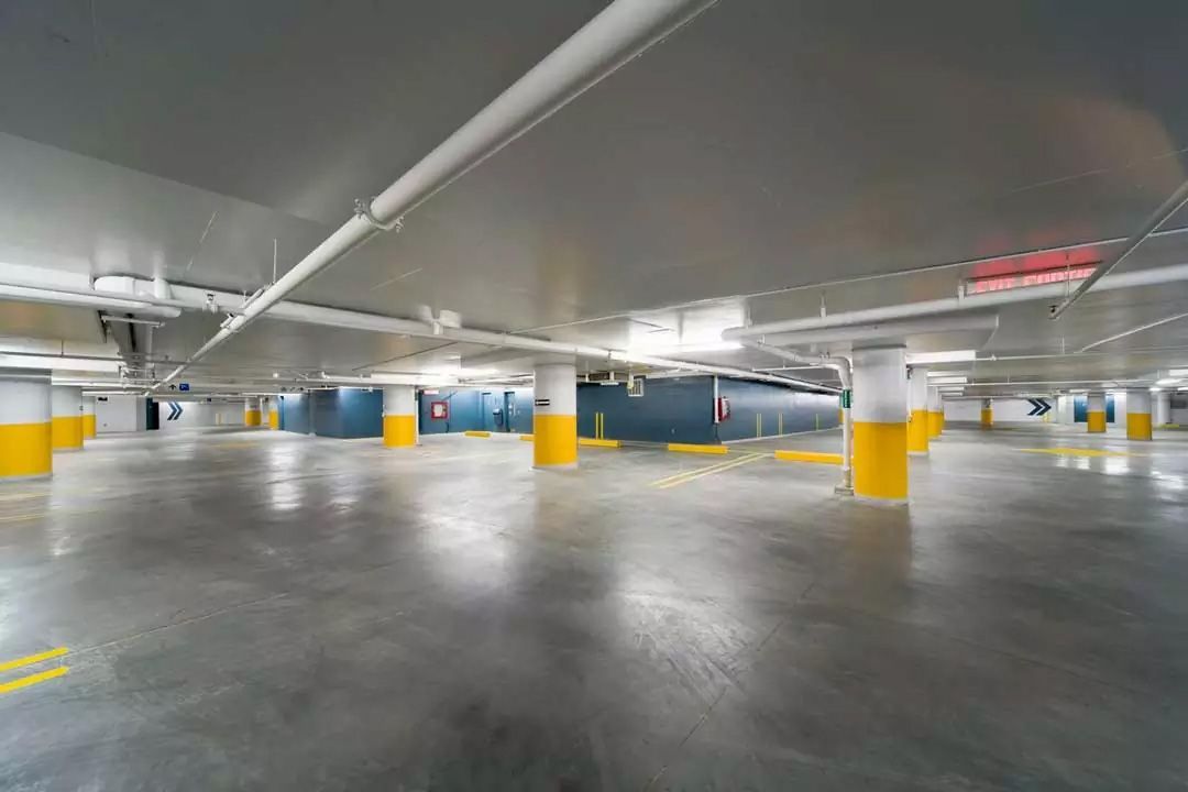 An empty parking garage with gray floors, white ceilings, and yellow-banded support columns.