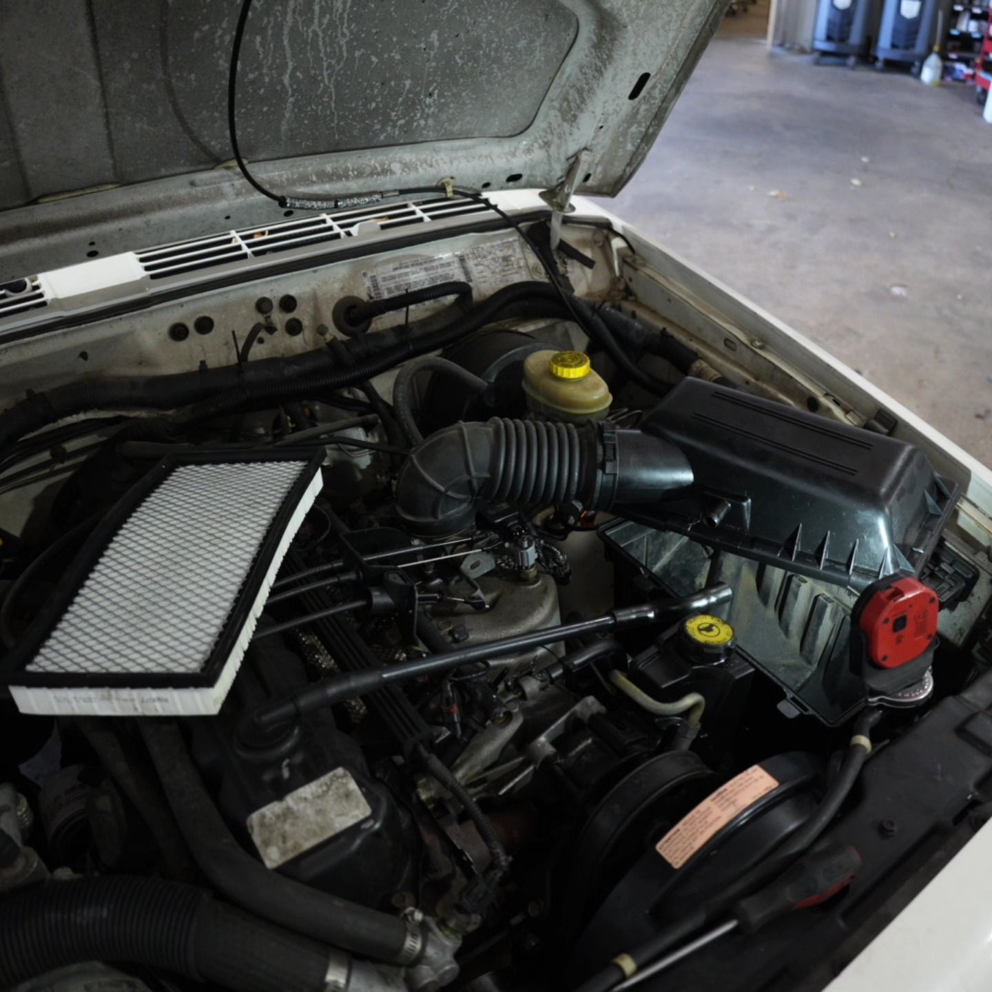 Open hood of white Jeep Cherokee with engine visible and a new air filter | Lenexa, KS