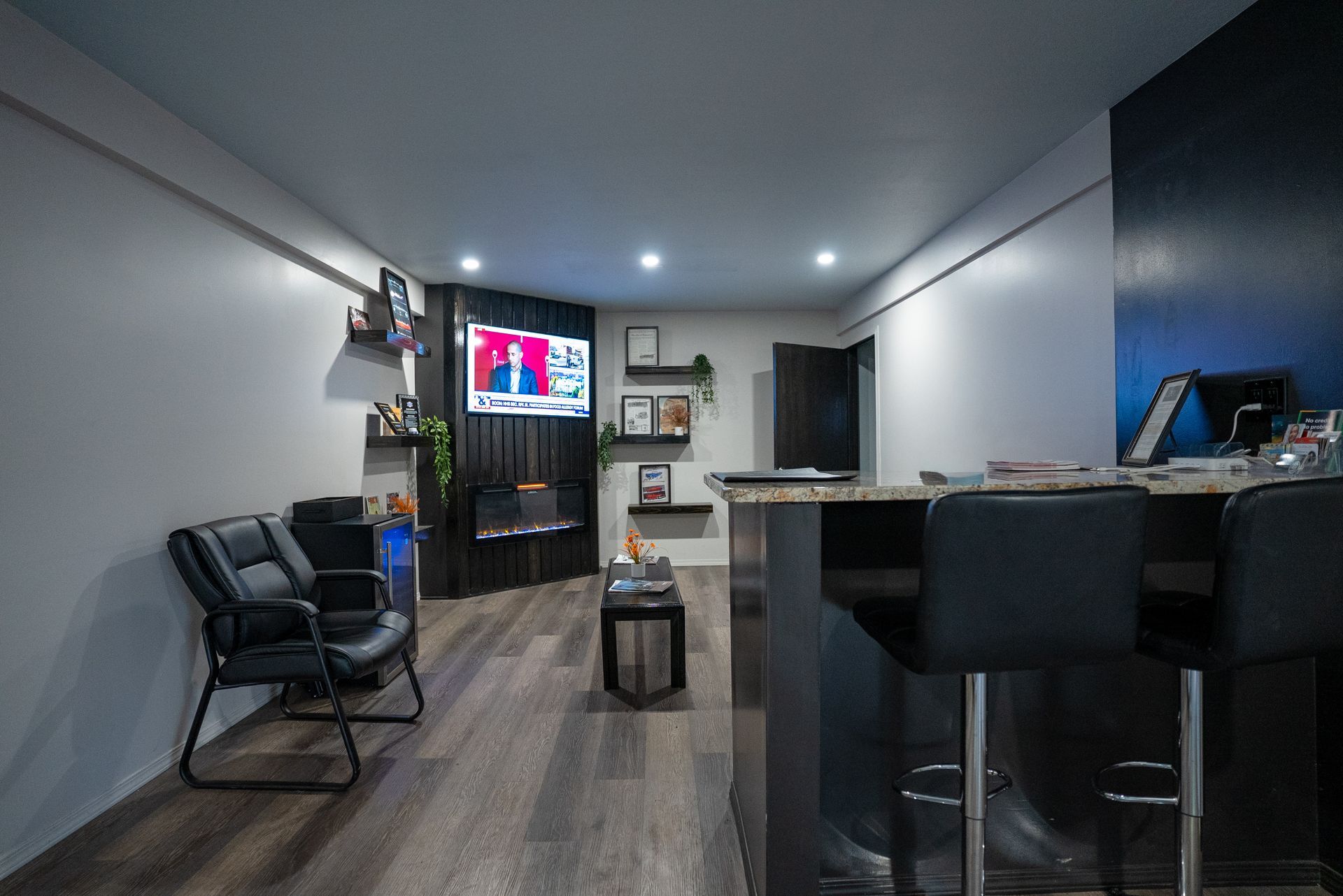 Modern waiting room with black bar, TV, and black leather chairs | Lenexa, KS