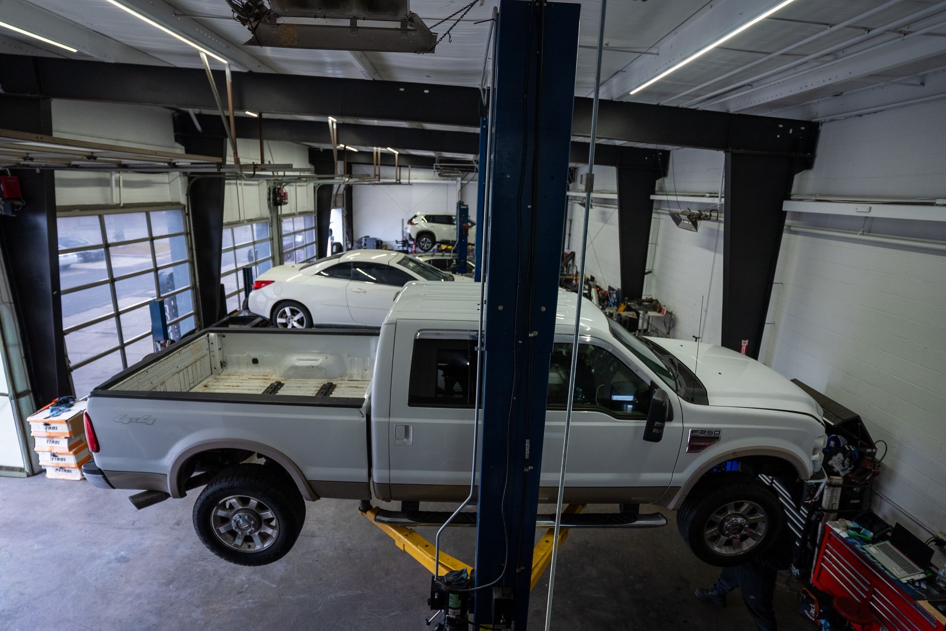 White pickup truck on a lift in a garage, a white car in the background | Lenexa, KS