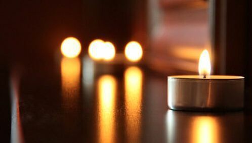 A group of lit candles are sitting on a table.