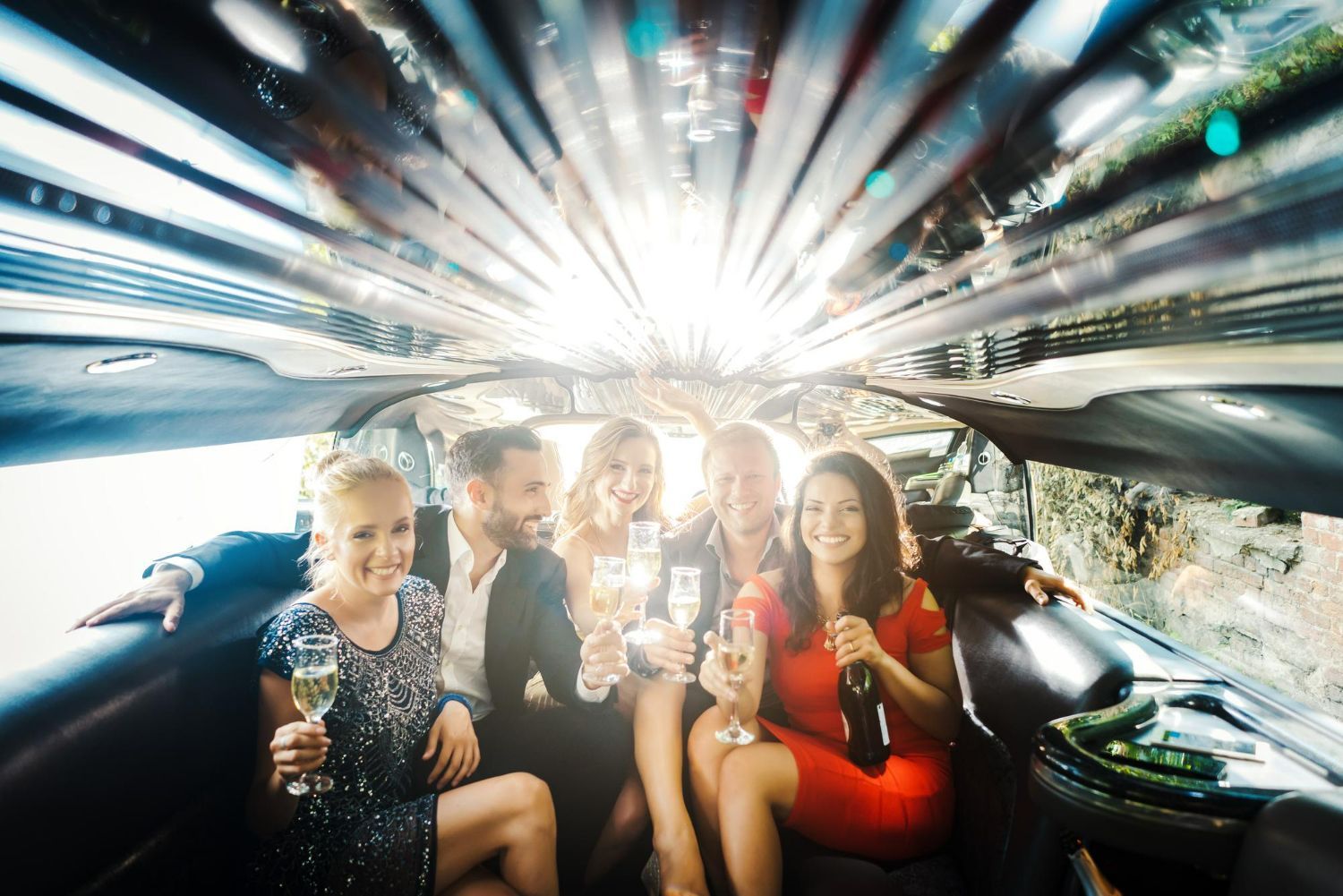 Group of friends celebrating with champagne in a limousine.