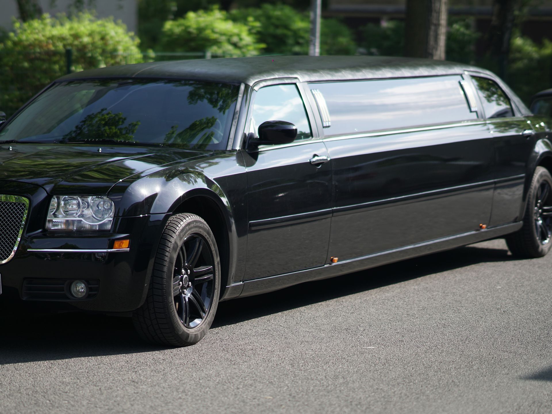 Black Chrysler 300 limousine parked on a paved road.
