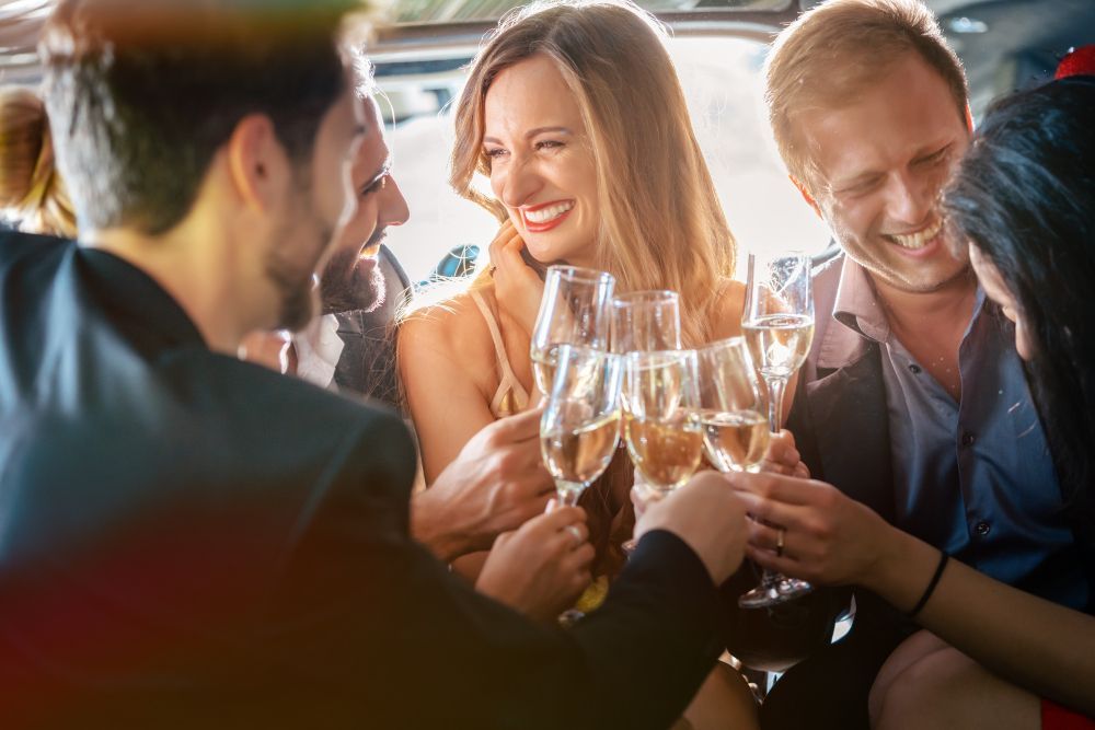 People toasting champagne in a limousine, smiling and celebrating.
