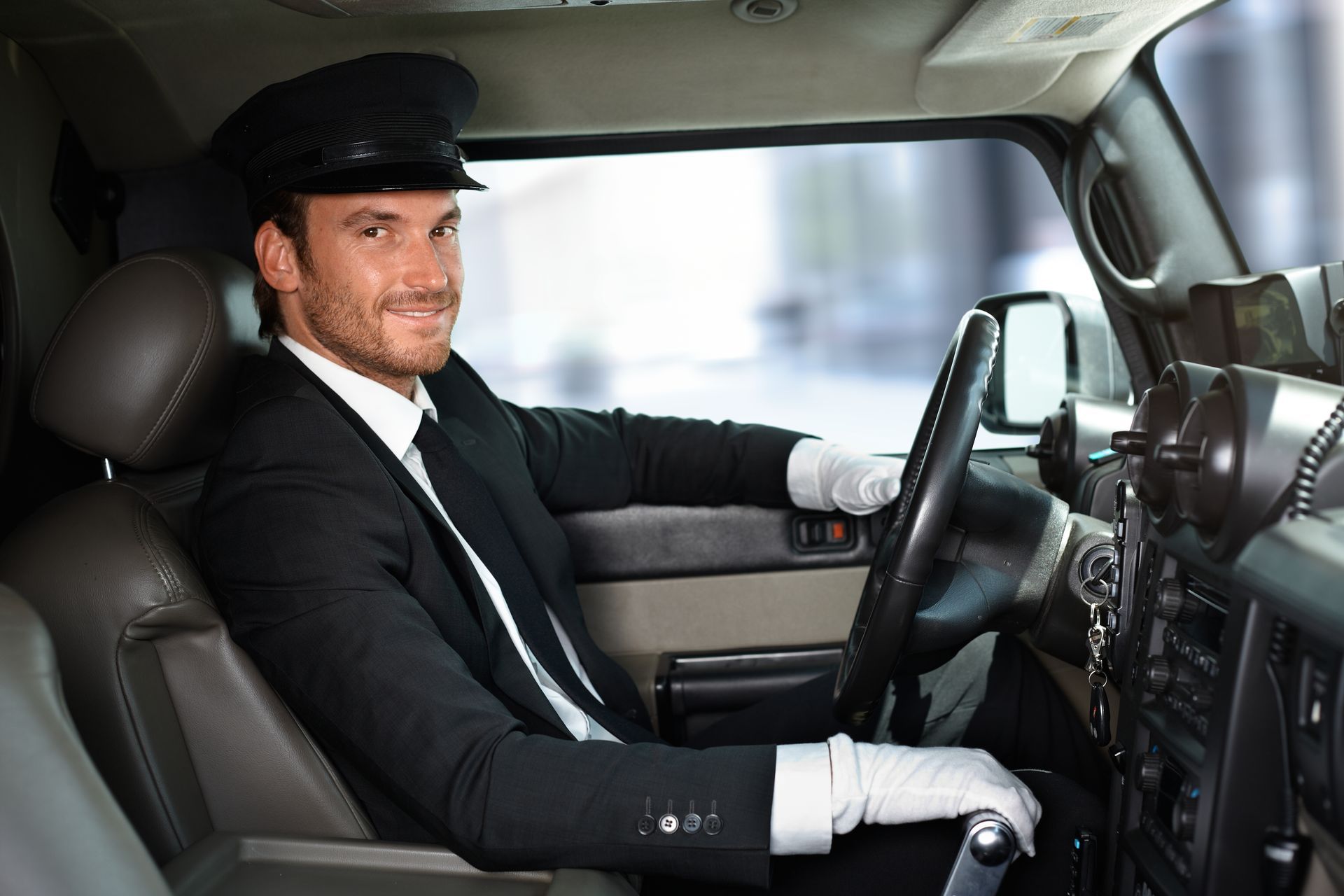 A man in a suit and tie is sitting in the driver 's seat of a car.