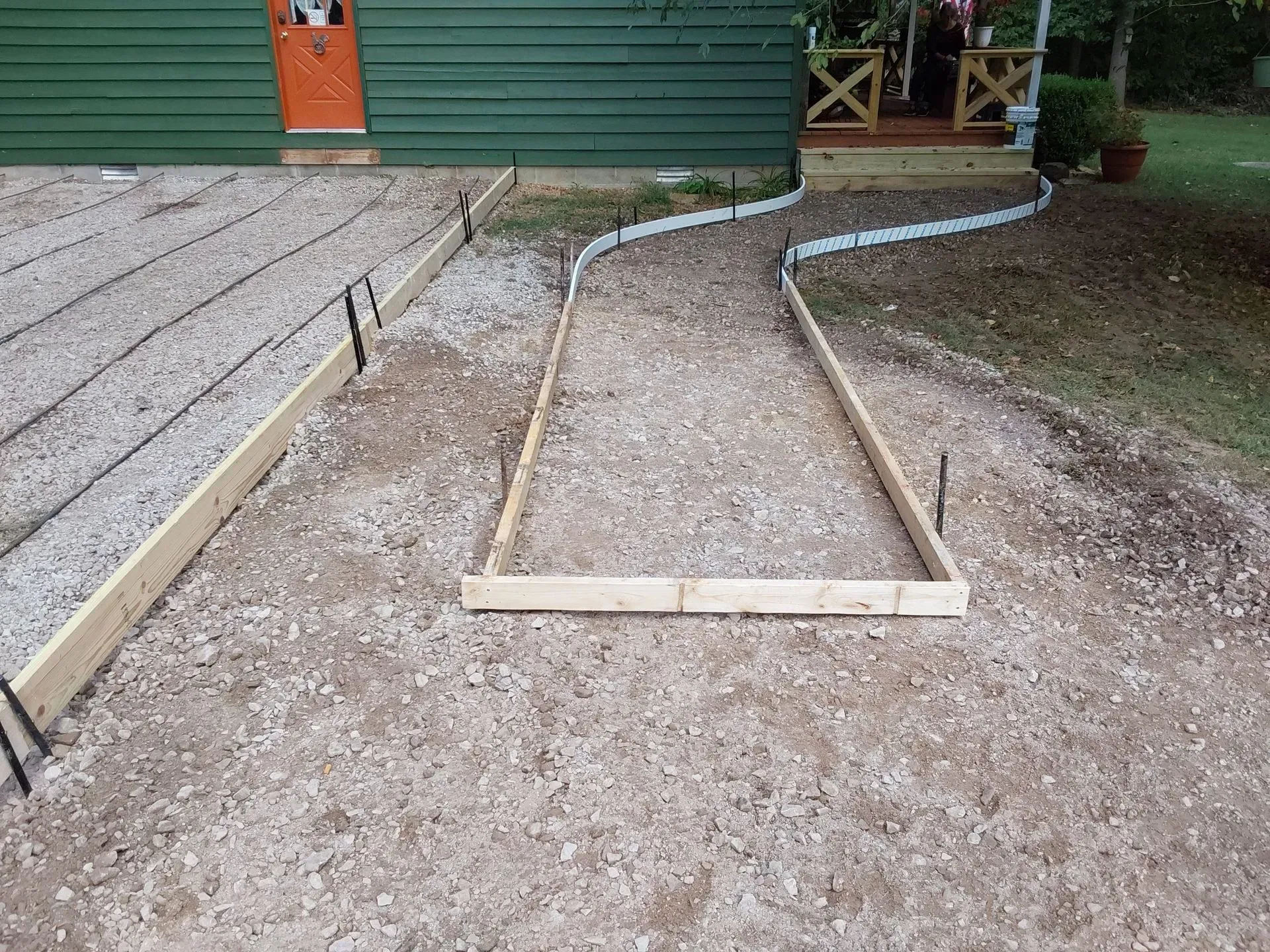 Wooden wheelchair ramp frame under construction beside a green building and deck.