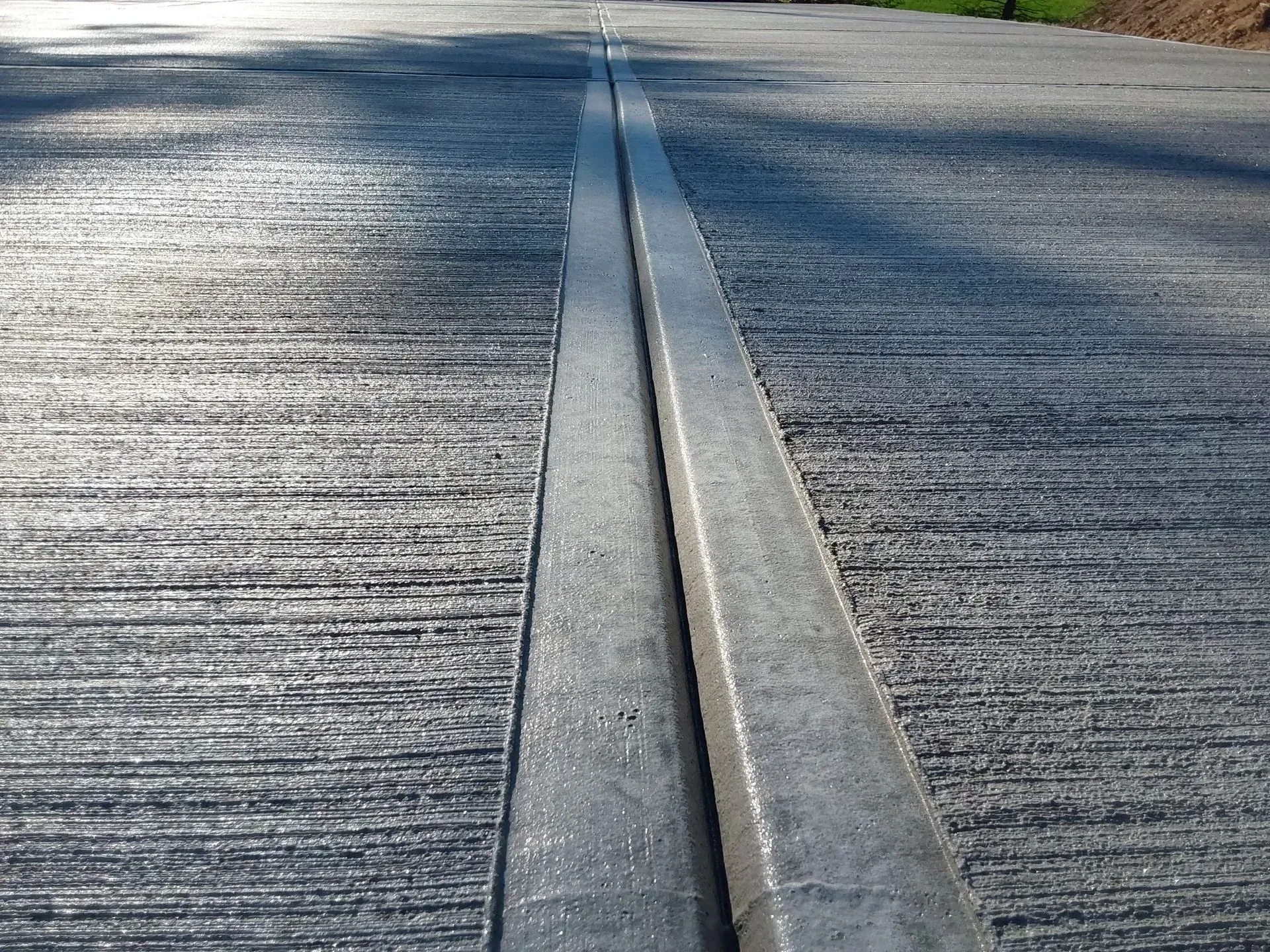 Concrete expansion joint in a paved surface with textured gray asphalt on both sides