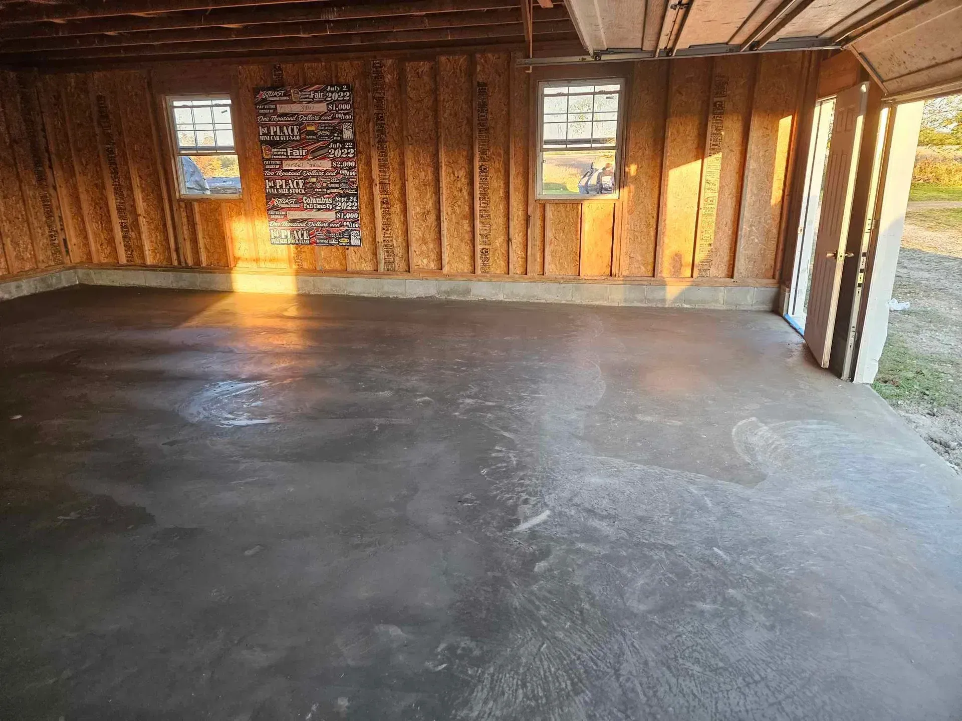 Empty wooden garage interior with concrete floor and two small windows