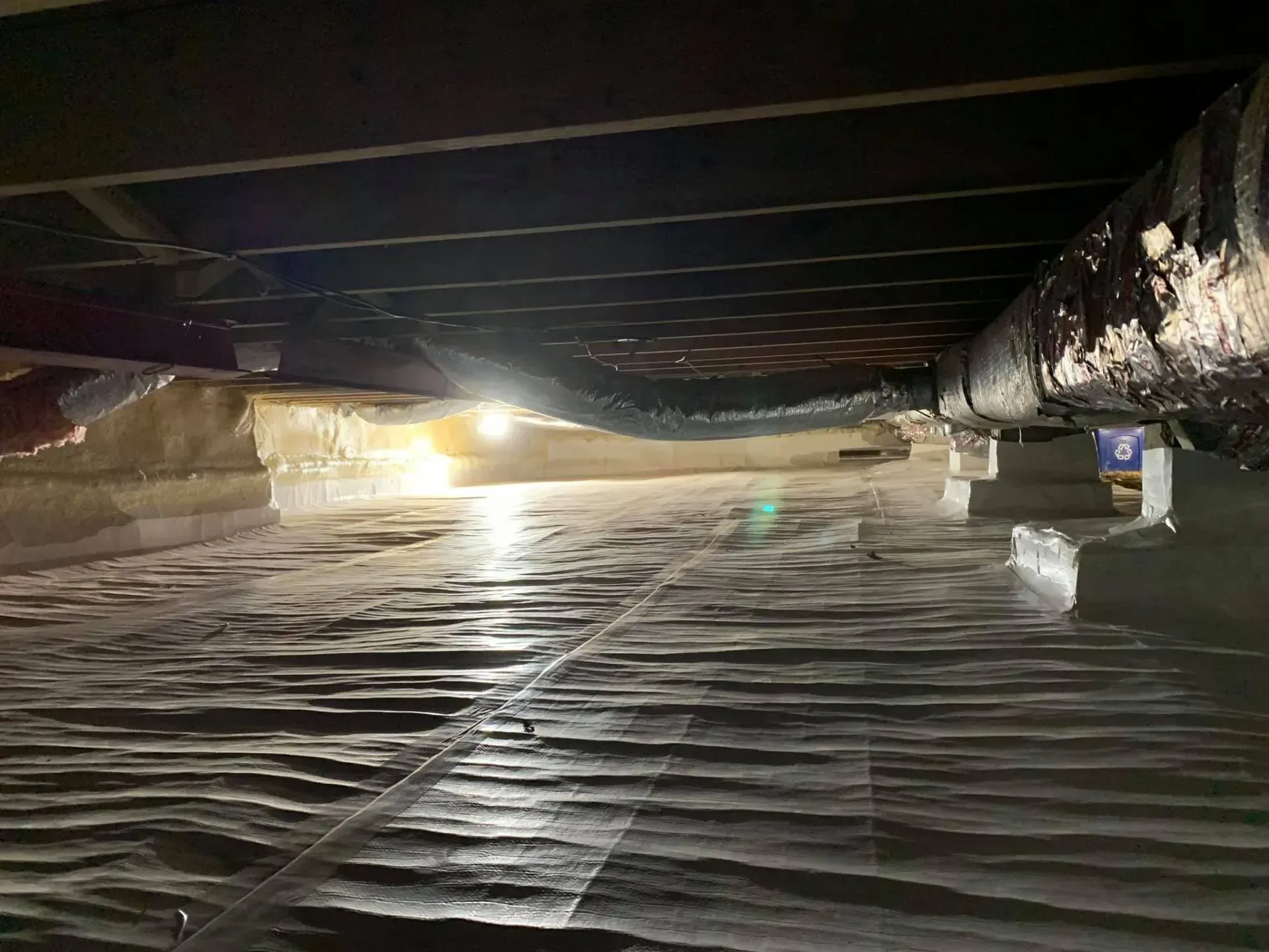 Underpass flooded with water, low bridge overhead, bright lights reflecting on the surface