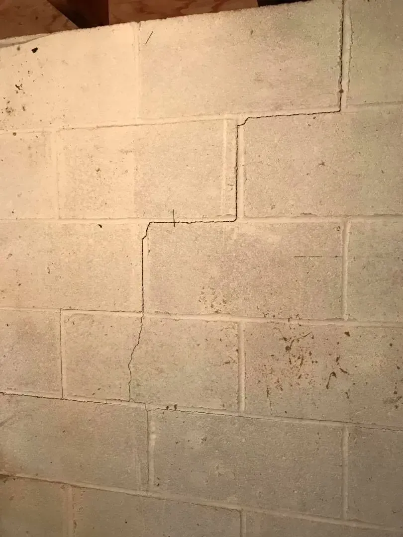 Beige cinder block wall with visible seams, stains, and a warm light gradient