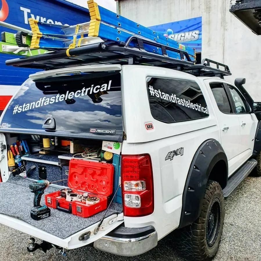A White Truck with A Toolbox in The Back Is Parked in Front of A Building — Stand Fast Electrical in Warwick QLD