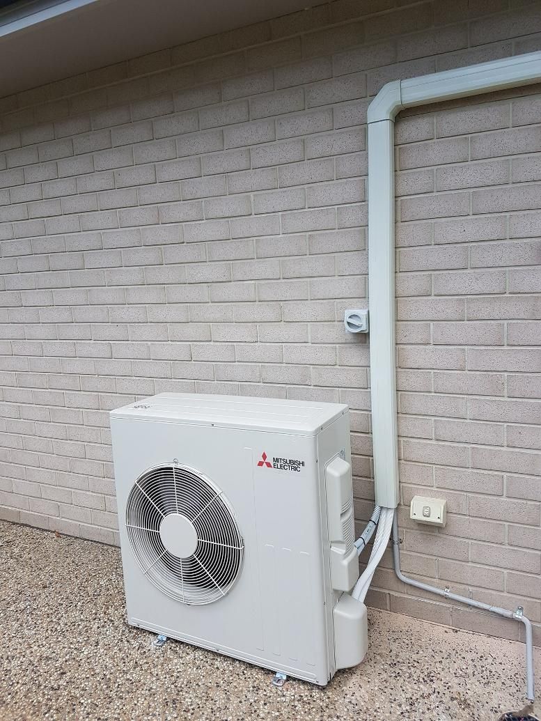 White Air Conditioner On The Brick Wall — Stand Fast Electrical Pty Ltd in Stanthorpe, QLD