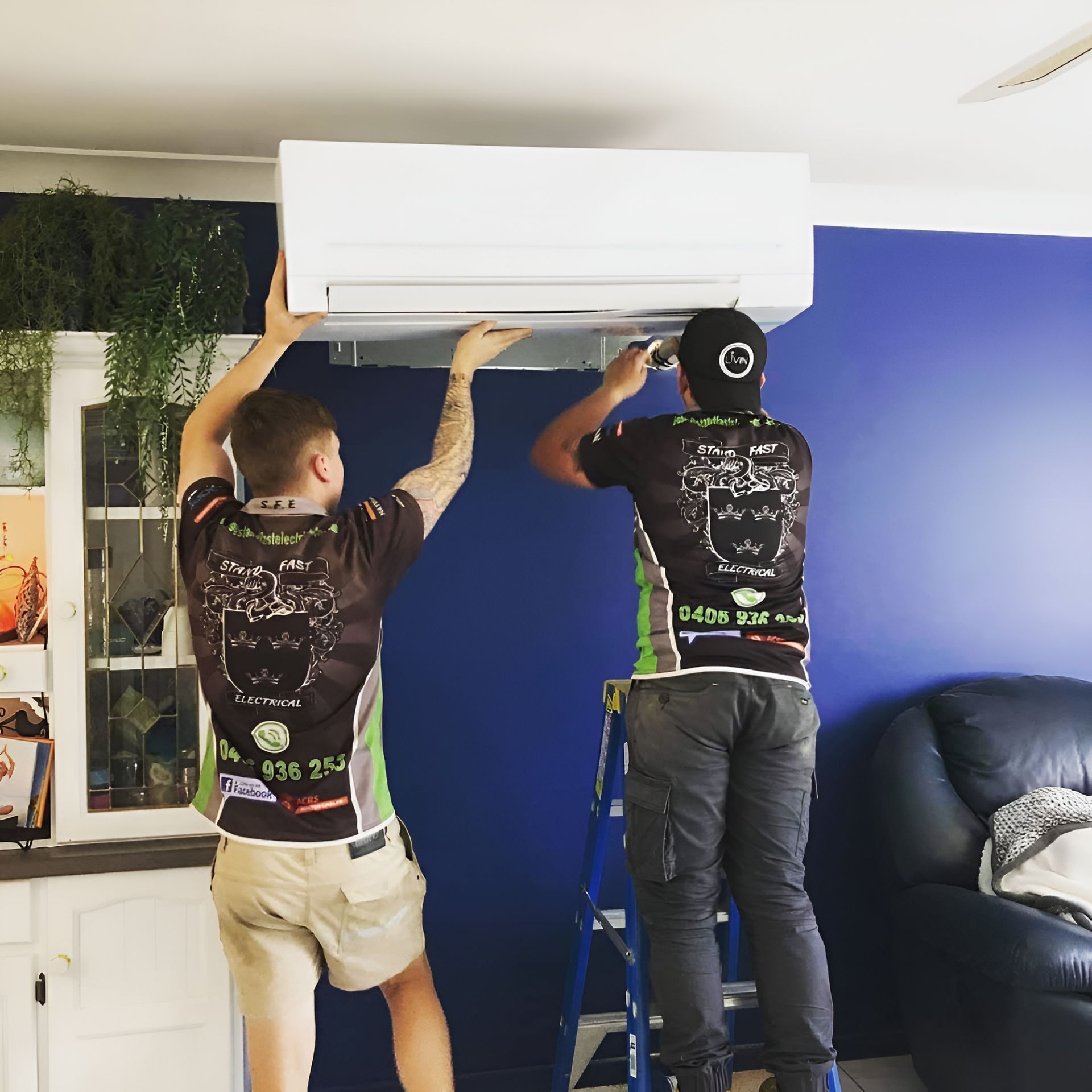 Two Men Installing Air Conditioner In The House — Stand Fast Electrical Pty Ltd in Warwick, QLD