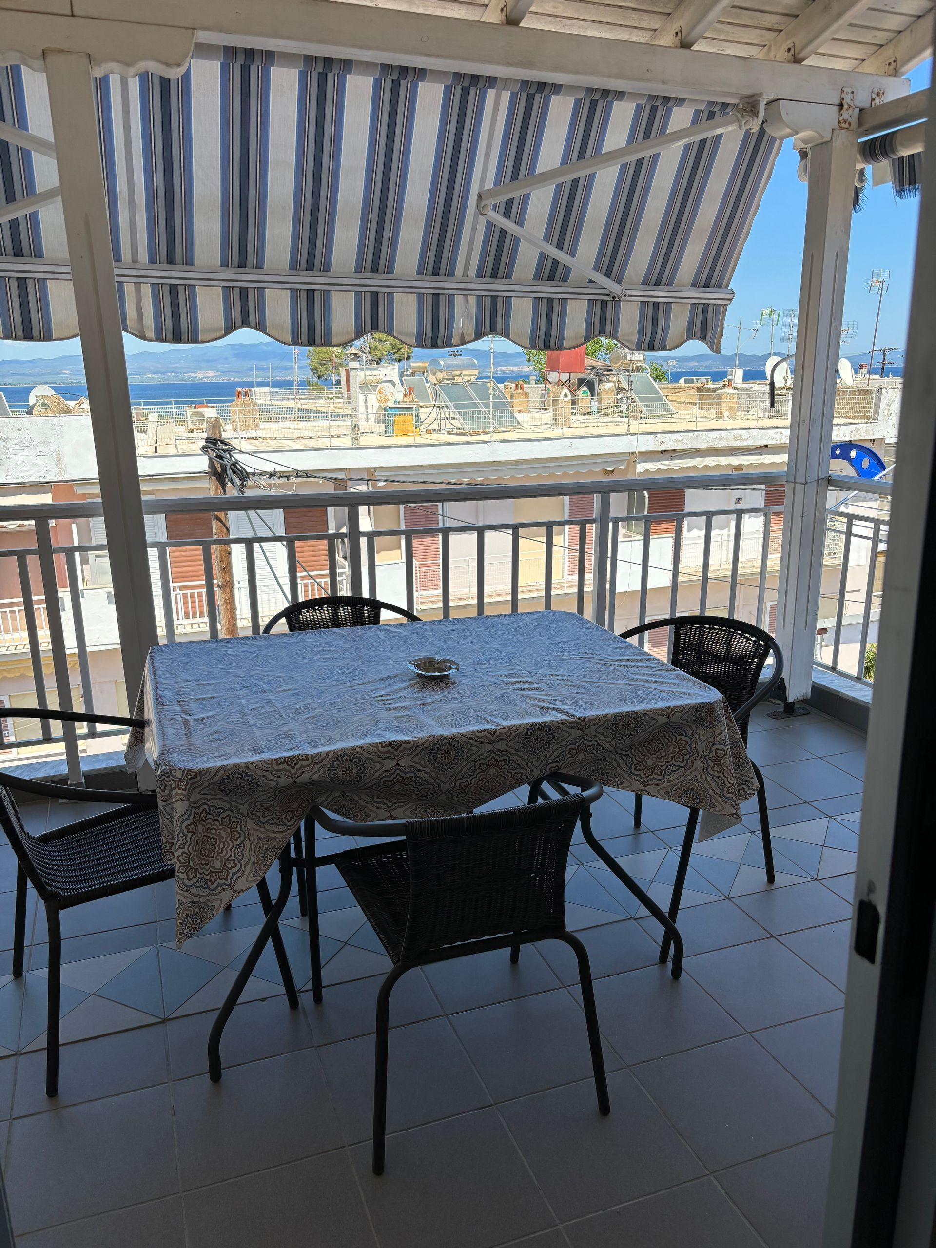 Snowy patio with a table and chairs under a striped awning, overlooking a winter landscape