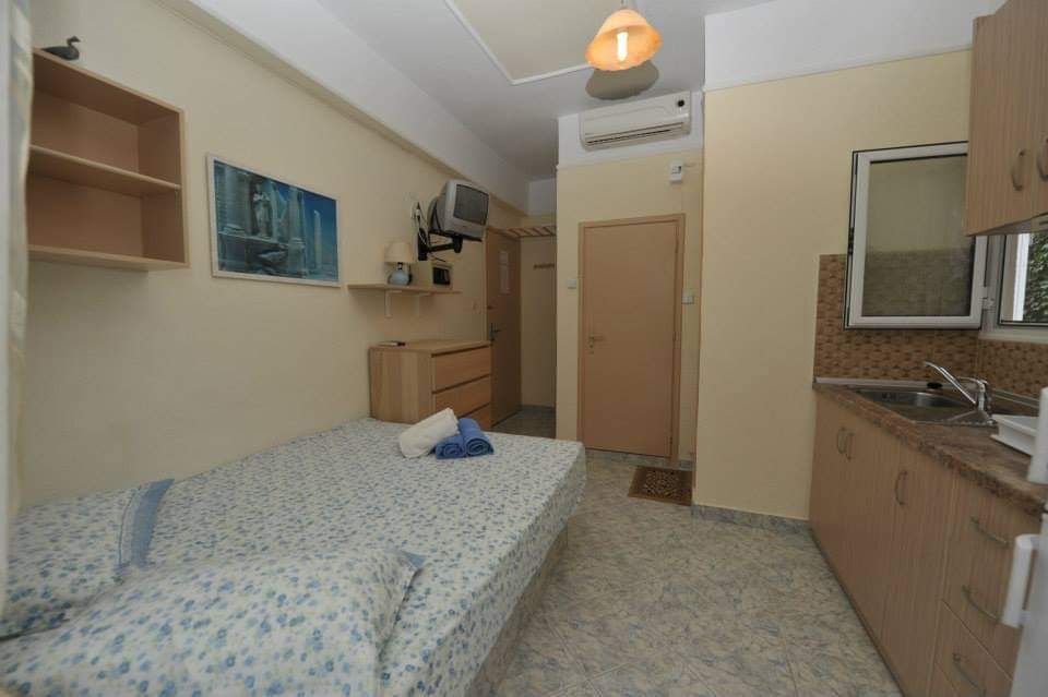 Small bedroom with a single bed, desk, wardrobe, and sink along the wall.