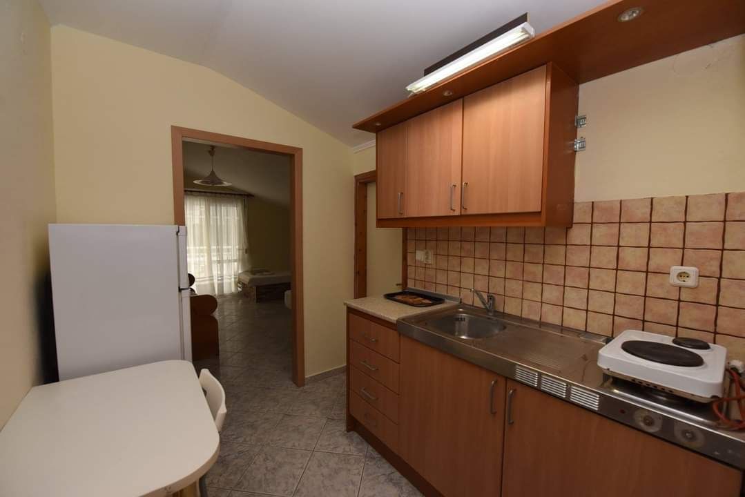Small kitchen with wood cabinets, granite counter, sink, refrigerator, and a doorway to a living room.