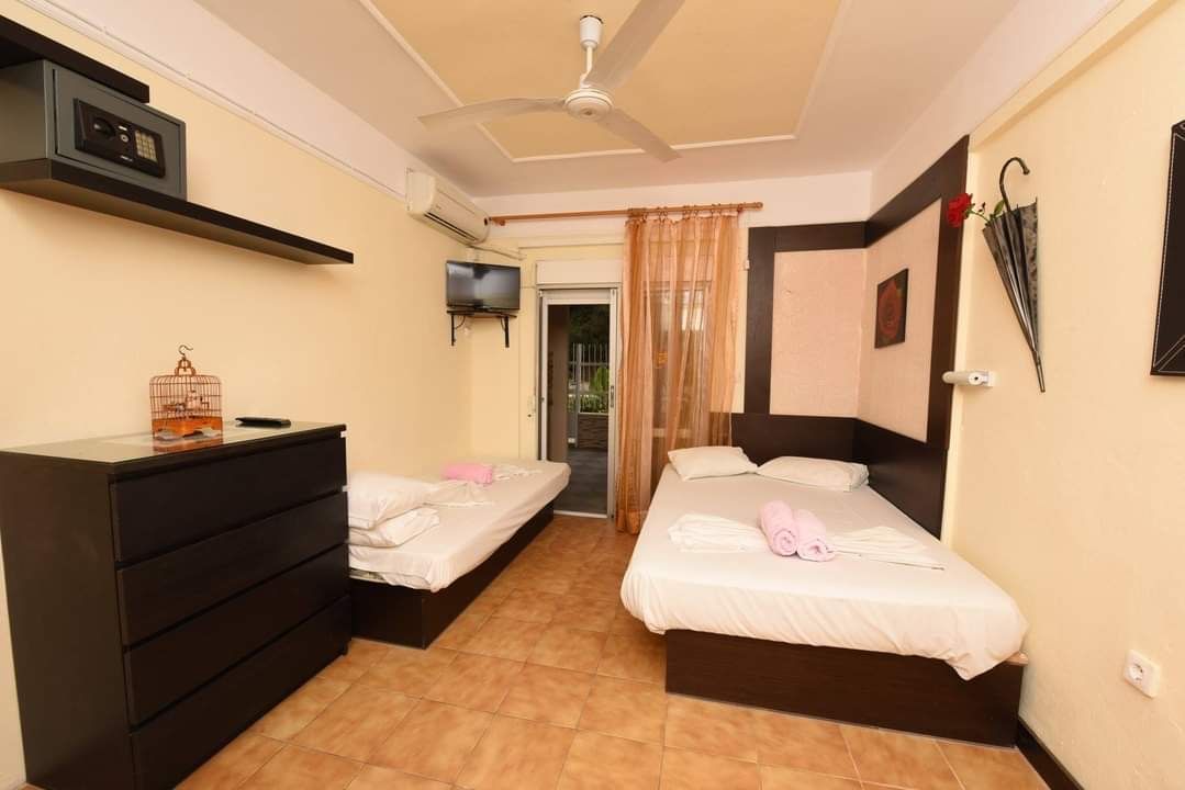 Small bedroom with two single beds, a dark dresser, and a window with curtains.