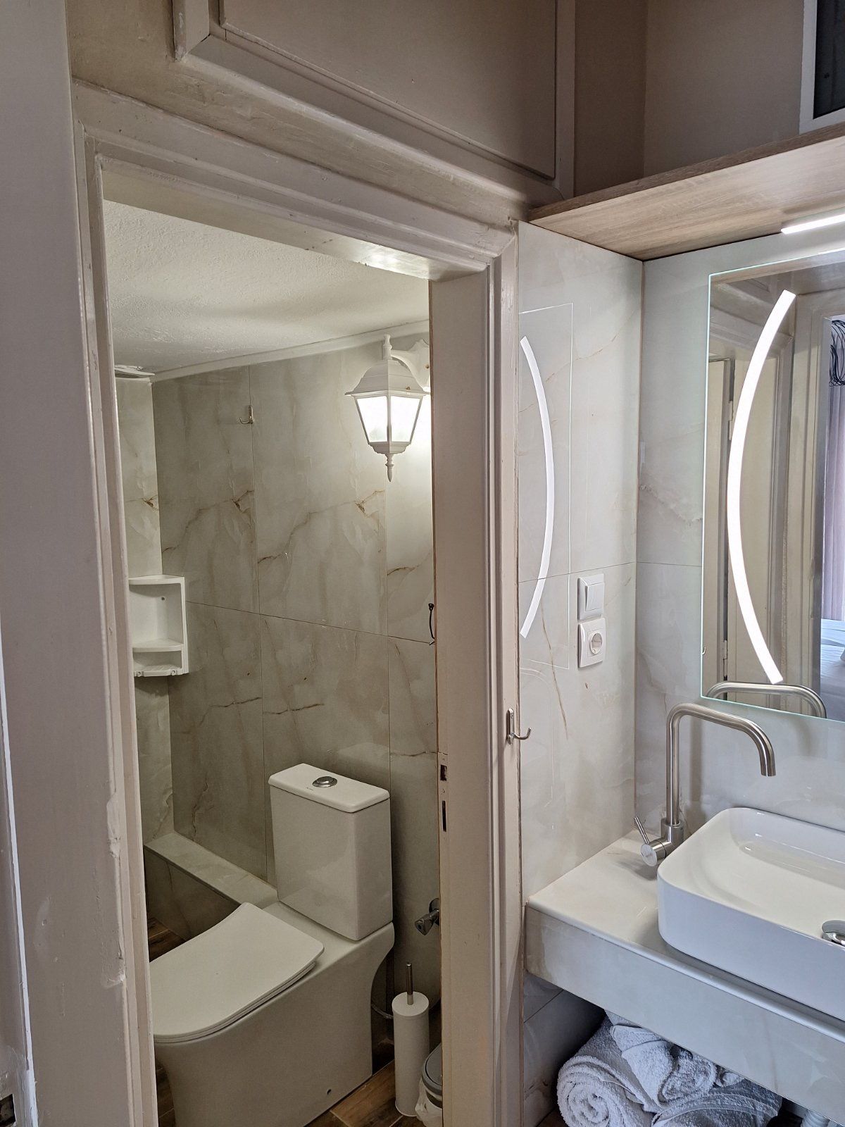 Small bathroom with shower-tub, toilet, vanity sink, and illuminated mirror.