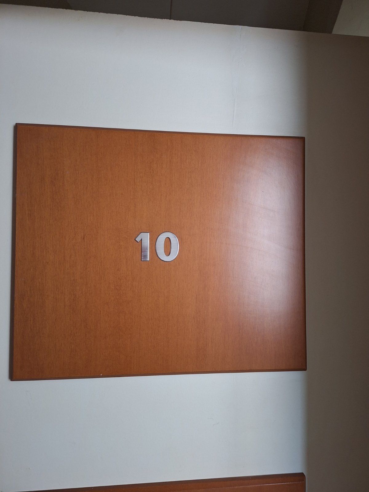 Brown door labeled “10” on a white wall.