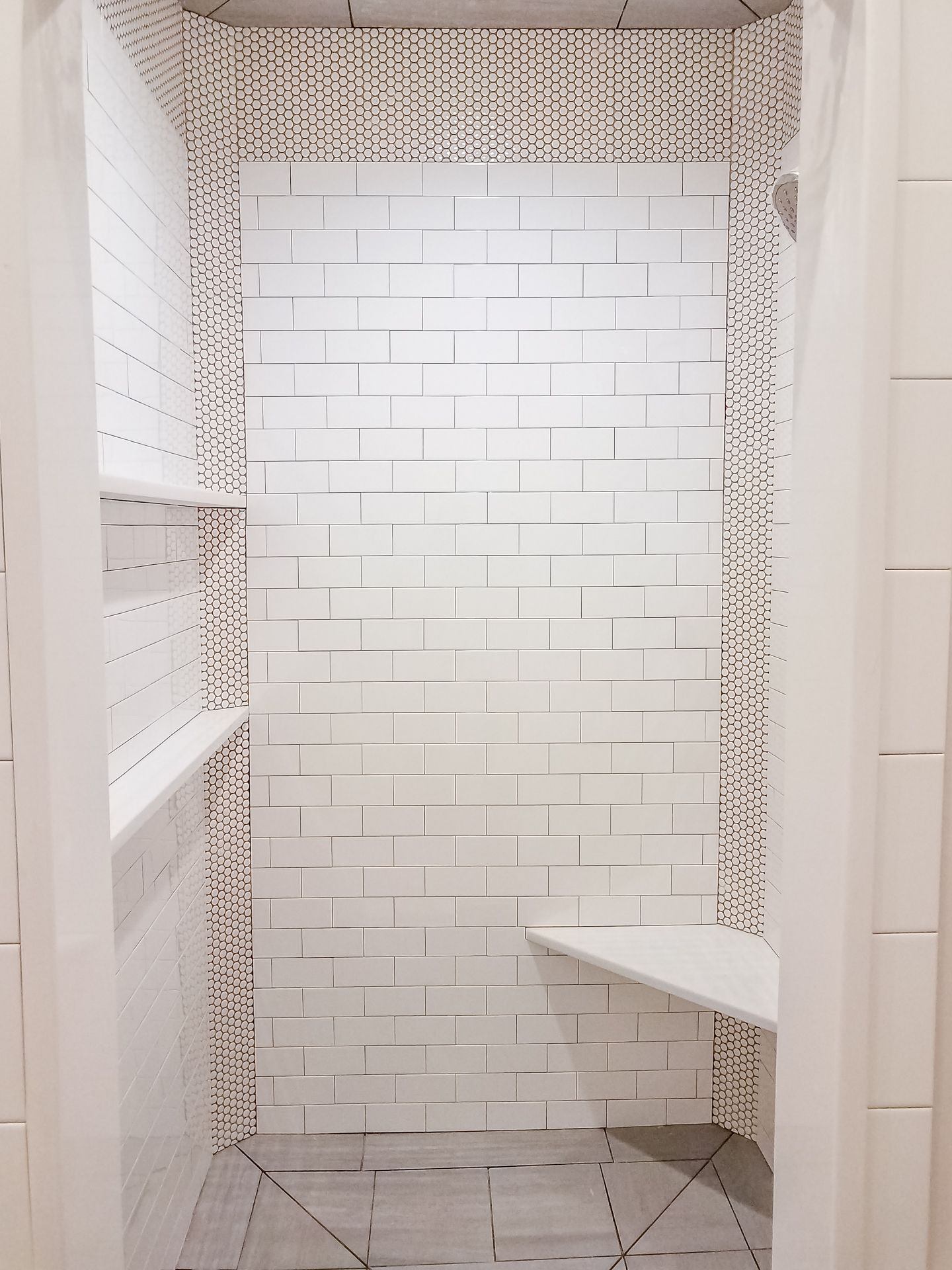 A bathroom with white tiles and a bench in it.