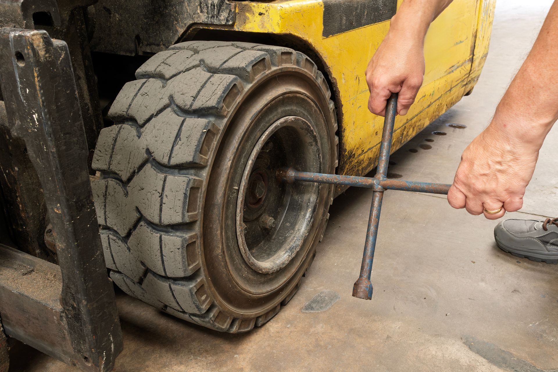 Mechanic working on a truck wheel hub with tools, underside of vehicle visible